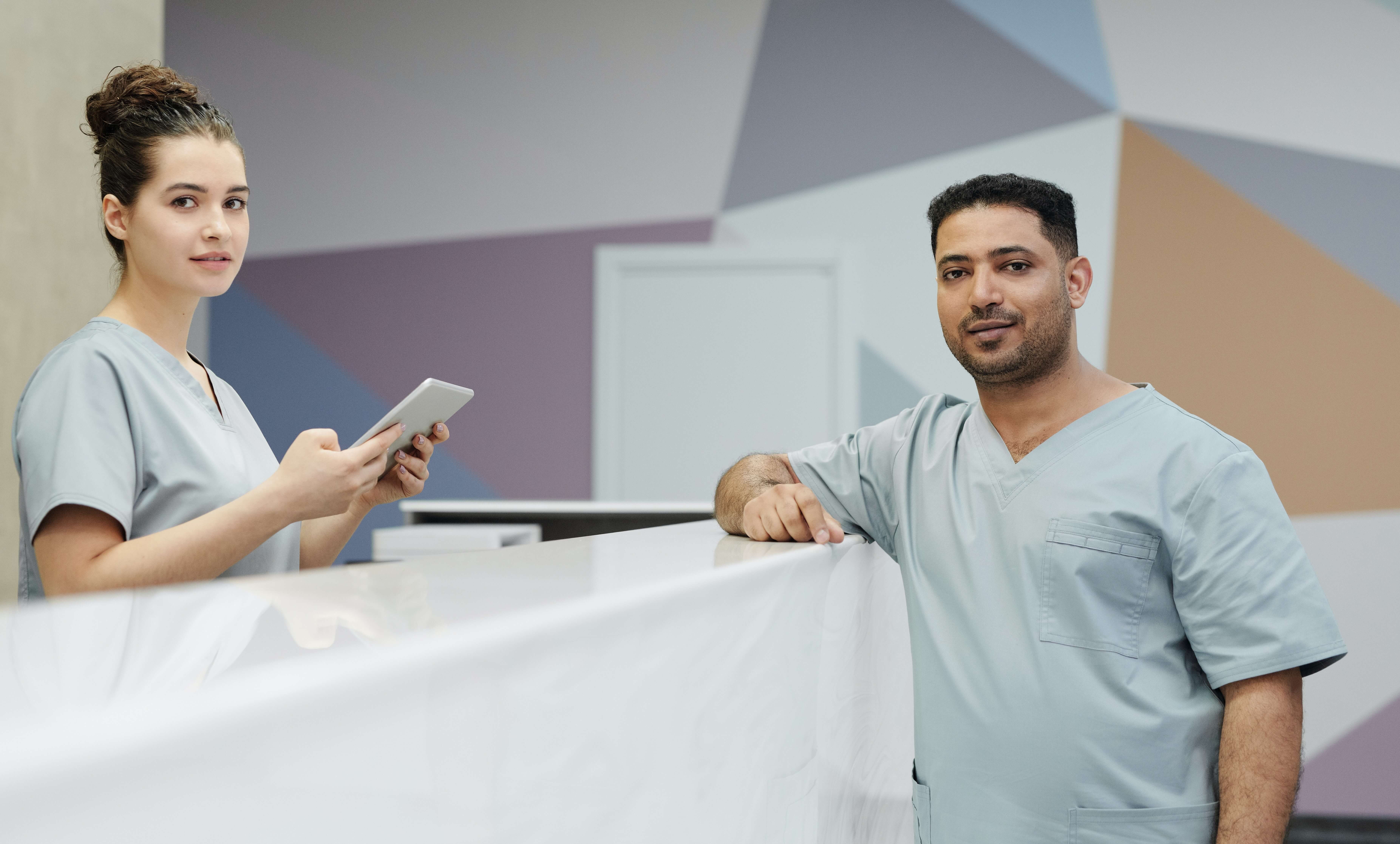 A receptionist and nurse standing at a reception desk