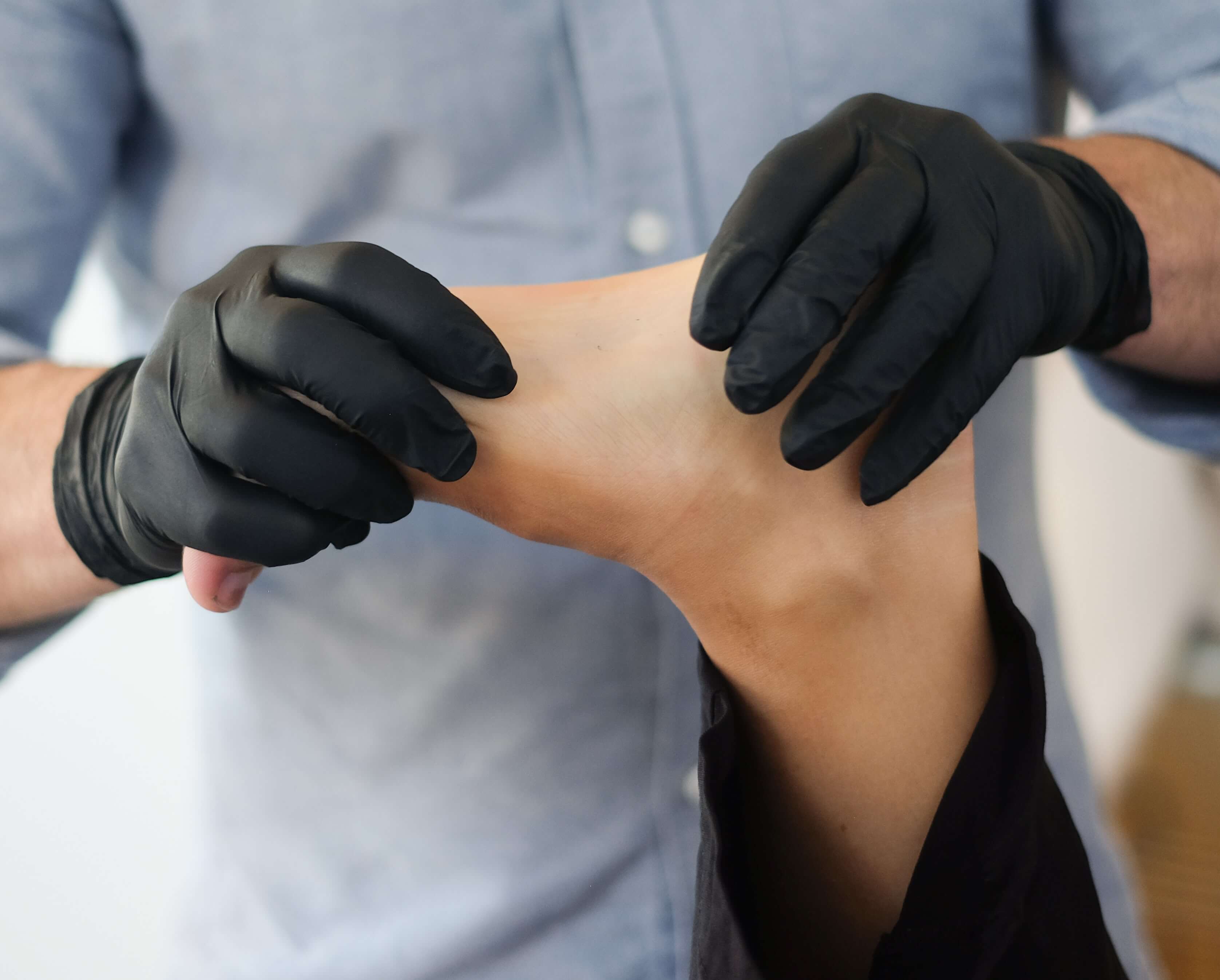 A physio holding a foot with gloved hands